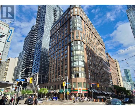 A tall building with a curved facade is located in a busy city intersection.