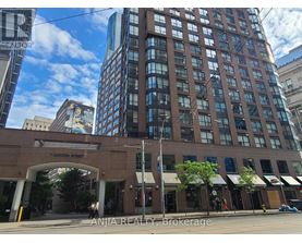 A street view of Carlton Street with a building in the foreground and a clear blue sky above.