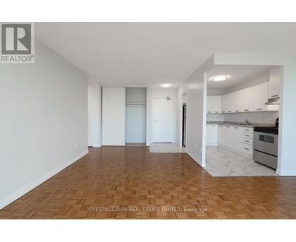 A spacious room with wooden flooring and white walls.