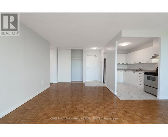 A spacious room with wooden flooring and white walls.