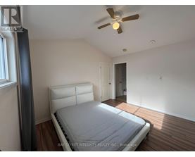 A bedroom with a bed, a ceiling fan, and a window.