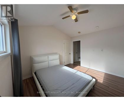 A bedroom with a bed, a ceiling fan, and a window.