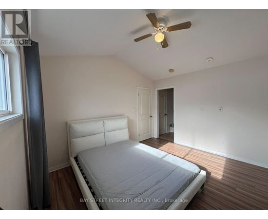 A bedroom with a bed, a ceiling fan, and a window.