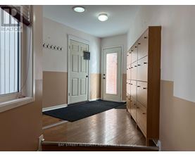 A hallway with a black mat on the floor and a wooden cabinet on the right.