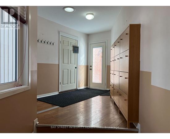 A hallway with a black mat on the floor and a wooden cabinet on the right.