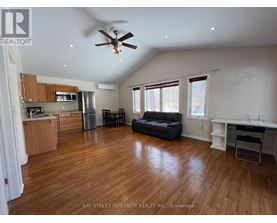 A spacious living room with wood flooring and a ceiling fan.