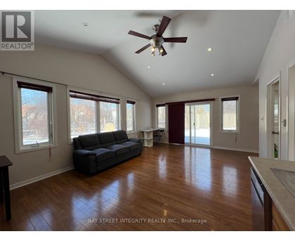 A spacious living room with a grey sofa and wooden flooring.