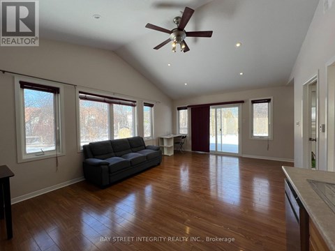 A spacious living room with a grey sofa and wooden flooring.