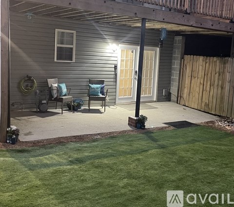 A patio area with a table and chairs under a lit up awning.
