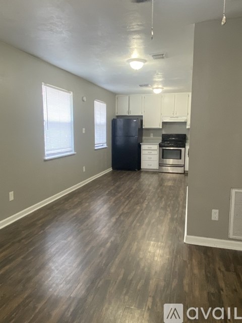 A kitchen with a black refrigerator and wooden floors.