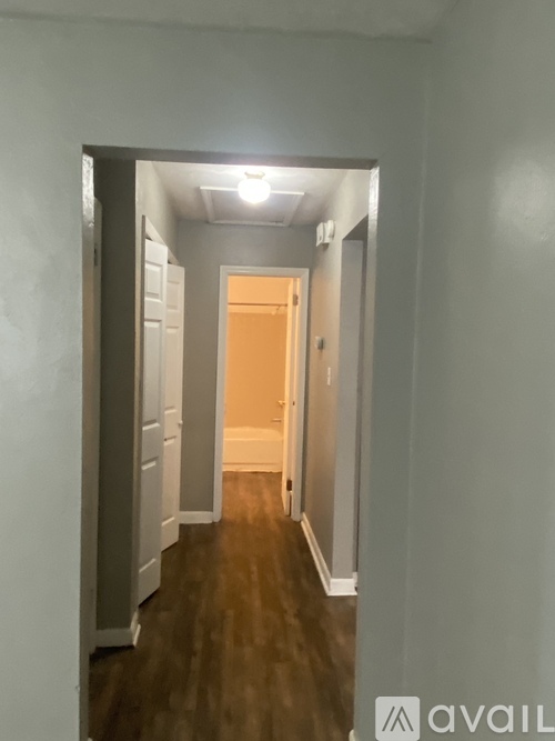 A hallway with a light on and a door at the end.