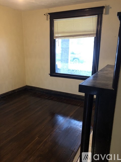A room with wooden floors and a window with blinds.