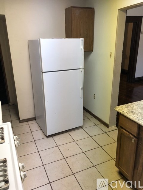 A white refrigerator in a kitchen with a tile floor.