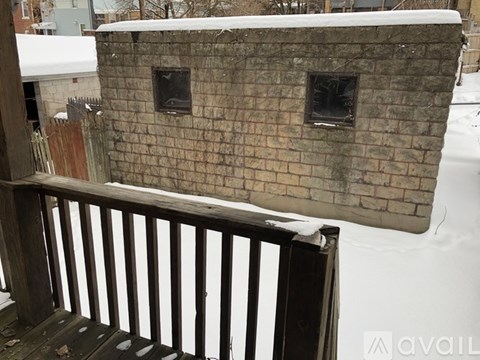 A small stone building with a wooden railing in front of it.