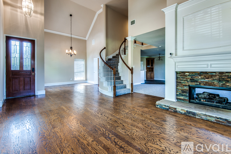 A spacious living room with wood flooring and a stone fireplace.