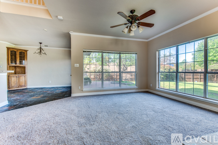 A spacious room with a ceiling fan and large windows.