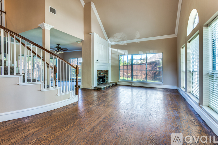 A spacious living room with wood flooring and a staircase.