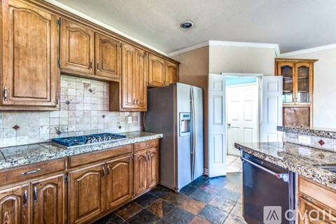 A kitchen with wooden cabinets and a granite countertop.