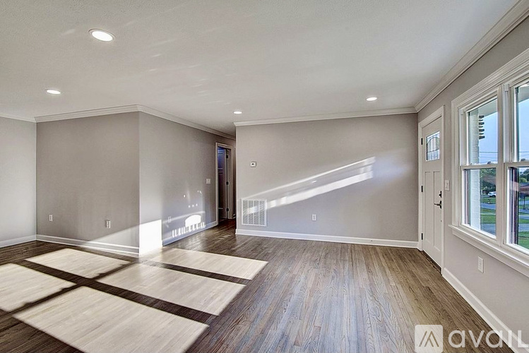 A spacious room with wooden floors and a large window.