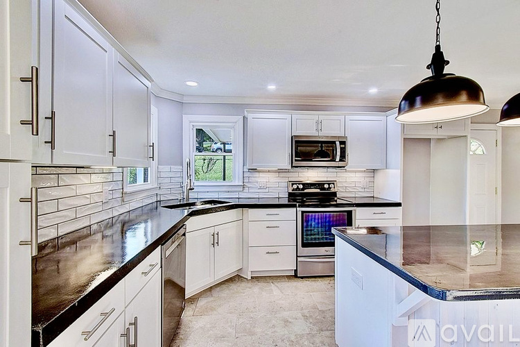 A modern kitchen with white cabinets and a black countertop.
