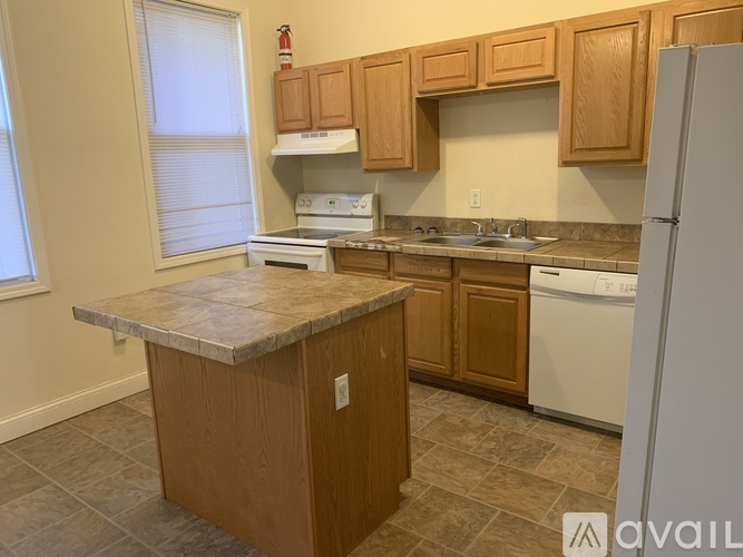 A kitchen with a white fridge, white stove, and wooden cabinets.