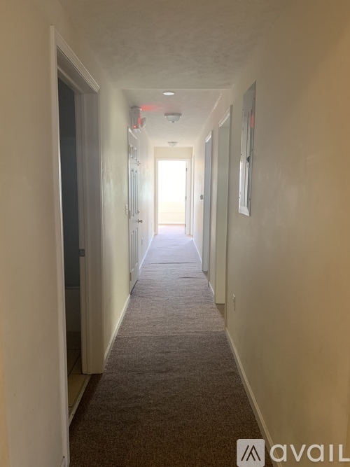 A long hallway with a carpeted floor and white walls.