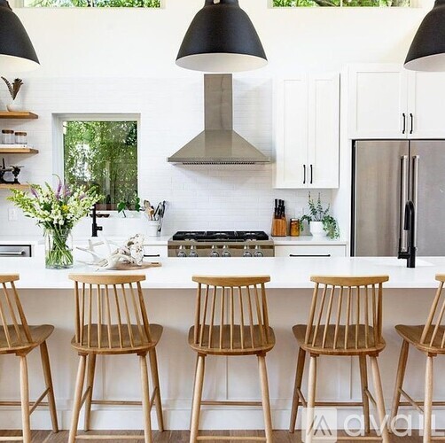 Four wooden chairs are placed in front of a white counter.