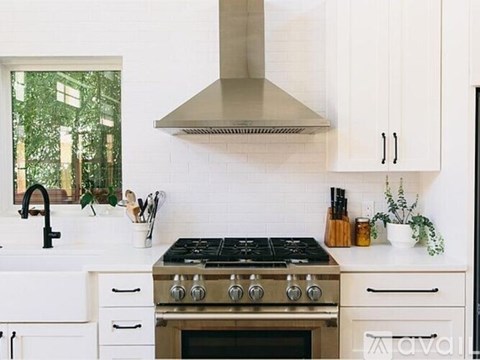 A modern kitchen with a stove top oven and white cabinets.