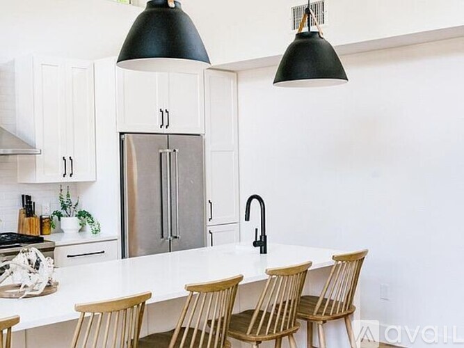 A kitchen with a white countertop and wooden chairs.