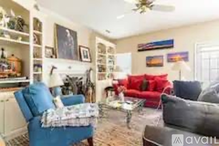 A living room with a red couch, a blue armchair, and a ceiling fan.