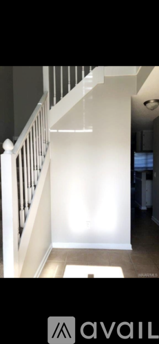 A hallway with a white railing and a light on the wall.