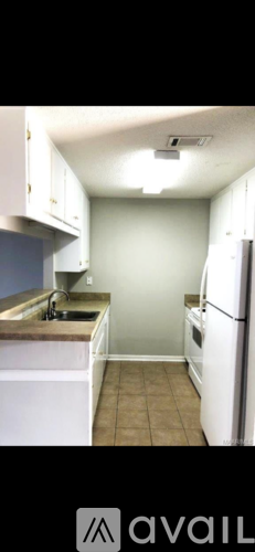 A kitchen with white cabinets and a white refrigerator.
