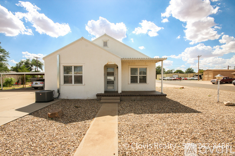 A white house with a gravel driveway in front.