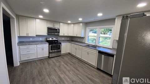 A kitchen with white cabinets and a grey floor.