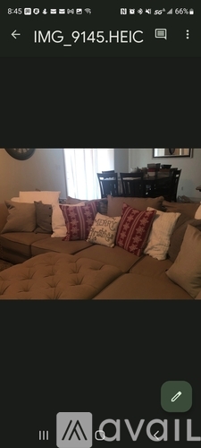 A brown couch with red and white pillows.