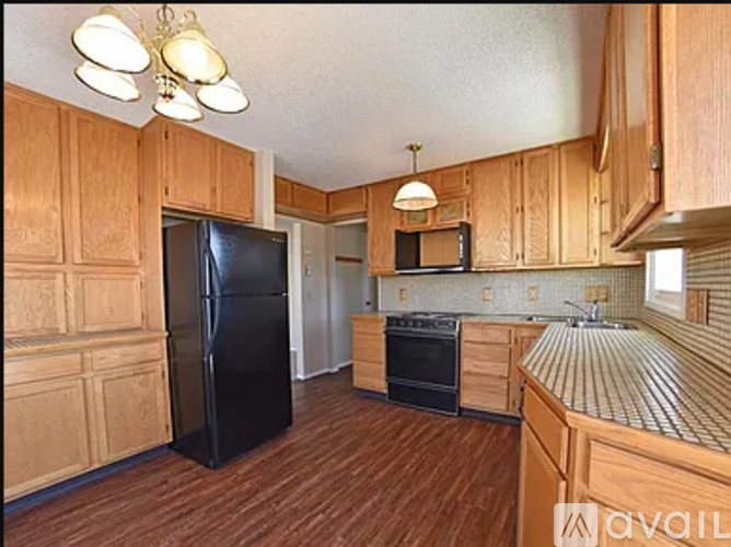 A kitchen with wooden cabinets and a black refrigerator.