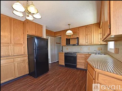 A kitchen with wooden cabinets and a black refrigerator.