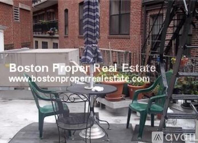 A patio with a table and chairs is set up outside a brick building.