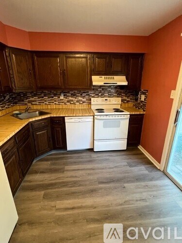 A kitchen with a white stove top oven and wooden cabinets.