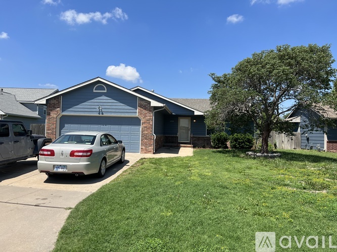 A silver car is parked in front of a house with a garage.