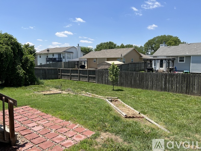 A backyard with a brick walkway and a wooden fence.