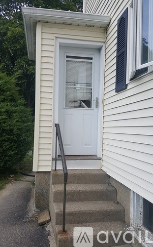 A white door with a glass window is on a house with a grey siding.