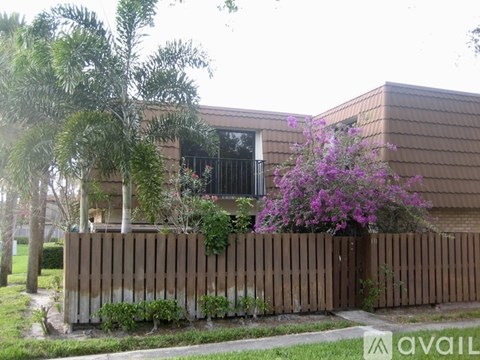 A house with a brown fence and purple flowers in front.