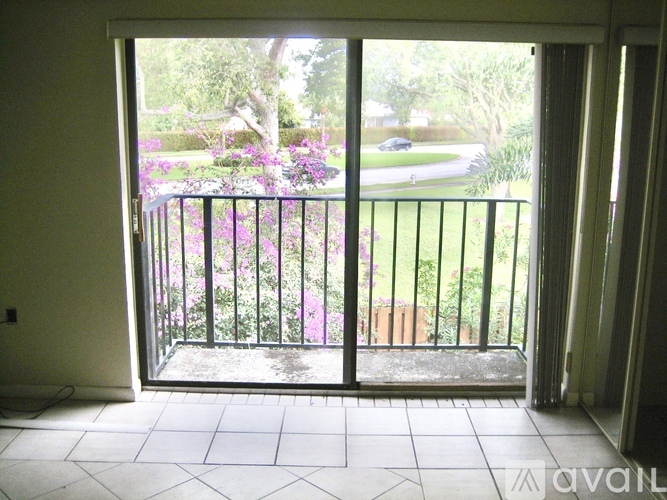 A balcony with a black railing and a view of a street and trees.