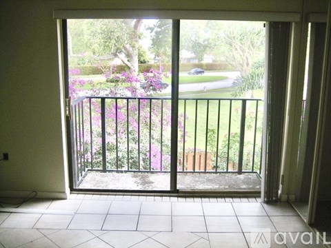 A balcony with a black railing and a view of a street and trees.