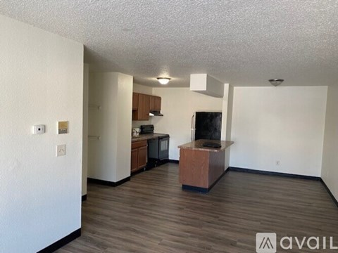 A living room with a television and a kitchen area in the background.