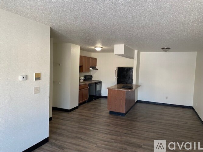 A living room with a television and a kitchen area in the background.
