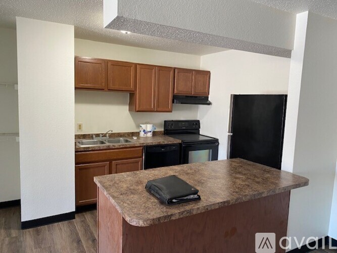 A kitchen with a black refrigerator and brown countertops.