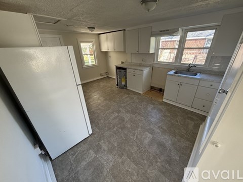 A kitchen with a white refrigerator and cabinets.