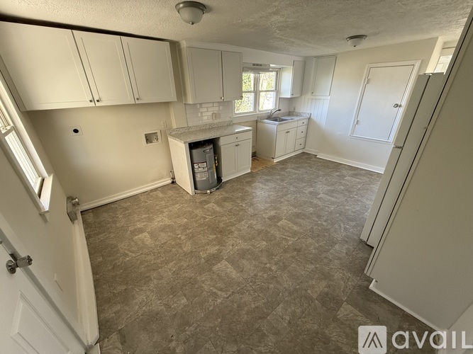 A kitchen area with white cabinets and a window.